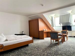a bedroom with a bed and a desk and a chair at ALFA Hotel - Superior in Karlsruhe