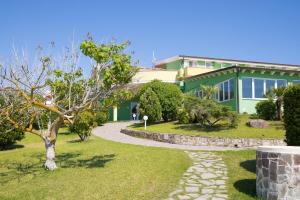 a green building with a walkway in front of it at Lu' Hotel Porto Pino in SantʼAnna Arresi