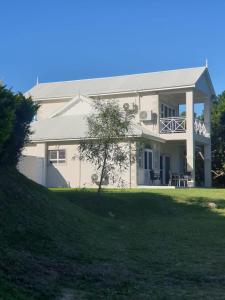 una gran casa blanca con un árbol delante en Caribbean Estates Villa Raiya- Recently Developed! 4 bedroom unit, en Port Edward