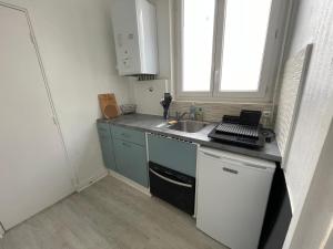 eine kleine Küche mit einem Waschbecken und einem Fenster in der Unterkunft Appartement à 200 mètres de la gare in Rouen