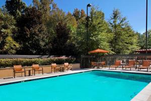 uma piscina com cadeiras e um guarda-sol em Courtyard Atlanta Airport West em Atlanta