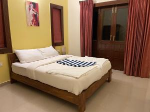 Schlafzimmer mit einem Bett mit weißer Bettwäsche und einem Fenster in der Unterkunft 3 Bedroom villa with Private Pool in North Goa in Assagao