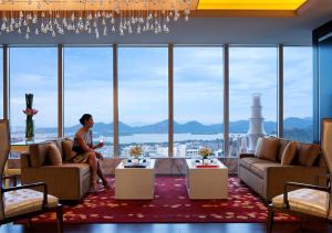 una donna seduta su un divano in una stanza con una grande finestra di JW Marriott Hotel Hangzhou a Hangzhou