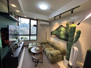 een woonkamer met een bank en een cactusschilderij bij The DRYM Space — Curated Staycation in Mandaluyong in Manilla