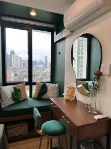 een woonkamer met een groene bank en een spiegel bij The DRYM Space — Curated Staycation in Mandaluyong in Manilla