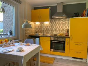 a kitchen with yellow cabinets and a white table at Ferienwohnung Amselnest in Lügde
