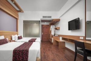 um quarto de hotel com duas camas e uma televisão de ecrã plano em Ohana Phnom Penh Palace Hotel em Phnom Penh