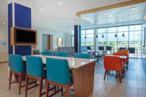 Holiday Inn Express - Starke, an IHG Hotel في ستارك: غرفة انتظار مع طاولات وكراسي وتلفزيون