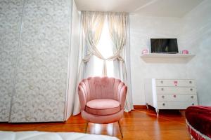 uma cadeira rosa num quarto com uma janela em Luxury Room em Montecatini Terme