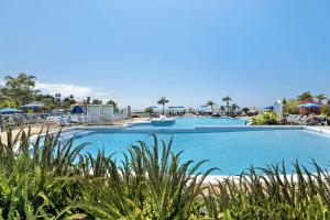 une grande piscine bleue avec des chaises et des parasols dans l'établissement La Quinta, à Santa Úrsula