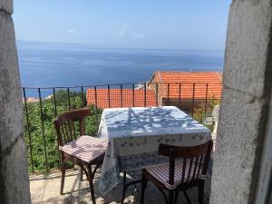 a table and chairs on a balcony with a view of the ocean at House Mate in Podgora