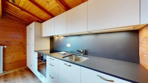 uma cozinha com armários brancos e uma pia em Apartment with spectacular view of the peaks em Crans-Montana