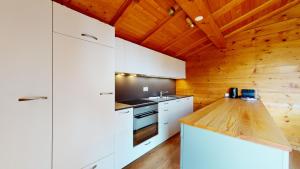 a kitchen with white cabinets and a wooden ceiling at Apartment with spectacular view of the peaks in Crans-Montana