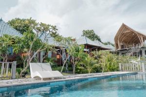 a villa with a swimming pool and a white lounge chair at Tawe Ocean Blue Villa Lembongan in Nusa Lembongan
