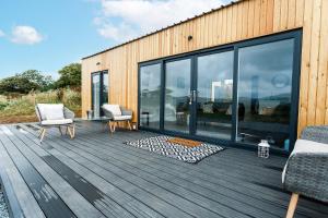 a wooden deck with two chairs and a building at Sea Glass Lodge in Gatehouse of Fleet