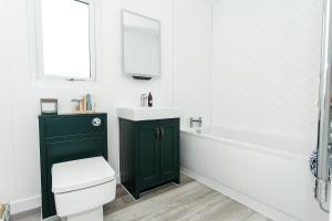Sea Glass Lodge في غايتهاوس اوف فليت: حمام مع خزانة خضراء وحوض استحمام ومغسلة