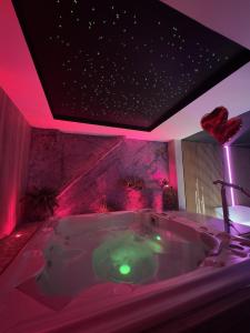 BonnevalにあるLes Secrets Rooms - Bonneval - Love Room - Spa et Hammam Privatifのピンクの照明が付いた大きなバスタブ付きのバスルーム