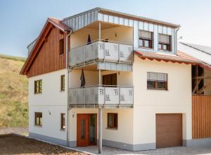 Cette maison blanche dispose d'un balcon et d'un toit marron. dans l'établissement Ferienwohnungen Thoma, à Königheim