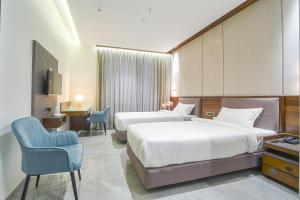 una camera d'albergo con due letti e una sedia di Hotel Devgiri Inn and Restaurant a Sāngli