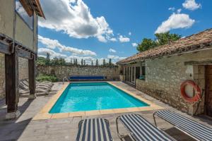 a swimming pool with chairs and a building at Le Moulin de Bernard in Saint-Pantaléon