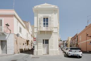 - un bâtiment blanc avec un balcon dans une rue dans l'établissement BassaMarea - Una sorpresa in Centro storico, à Carloforte