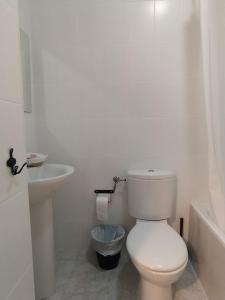 Baño blanco con aseo y lavamanos en Hostal El Pinar, en Montecorto