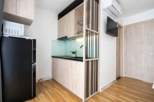 uma cozinha com armários de madeira e um frigorífico preto em HAYA BAC HAI Apartments em Ho Chi Minh