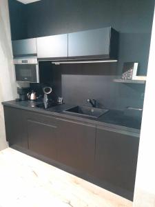 a black kitchen with a sink and a microwave at Les Secrets Rooms - Bonneval - Love Room - Spa et Hammam Privatif in Bonneval