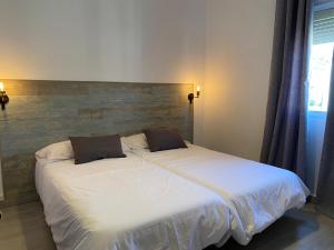 een slaapkamer met een bed met witte lakens en kussens bij Hostal El Pinar in Montecorto