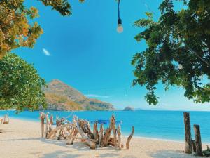 a beach with a bunch of logs on the sand at Sylvia Beach Villa in Labuan Bajo