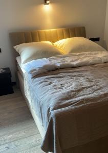 un letto con lenzuola e cuscini bianchi in una stanza di Boutique Suites Sylt - Kliffkante - Opening August 2023 a Kampen