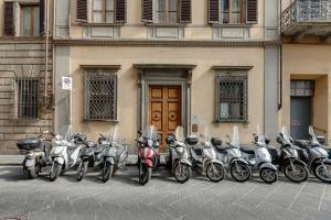uma fila de scooters estacionadas em frente a um edifício em Mamo Florence - Aperol & Spritz Apartments em Florença