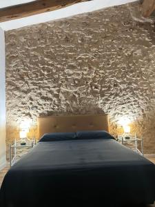 ein Schlafzimmer mit einem Bett und einer Steinmauer in der Unterkunft Via ca´ls Avis in Campredó