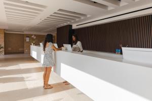 a woman standing at a counter in a lobby at Marelive - CDSHotels in Torre dell'Orso
