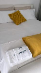 a white bed with white towels and a yellow pillow at Cataleya Baia del Carpino Scalea in Scalea