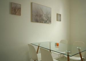 Apartment Edda في سنفتنبرغ: غرفة طعام مع طاولة زجاجية وكراسي بيضاء