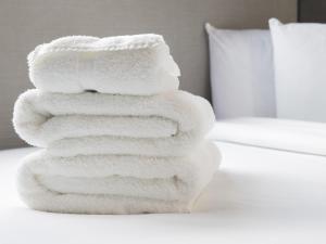 a stack of white towels sitting on top of a bed at Bloc Hotel London Gatwick Airport in Horley