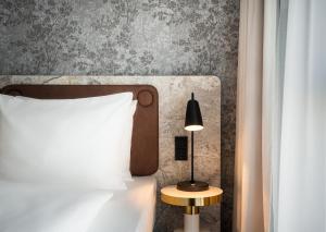 a bedroom with a bed and a lamp on a table at Arthotel ANA Amber in Rostock