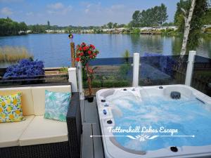 a hot tub on a deck with a view of a river at Meridian Tattershall Lakes Escape - Lakeside lodge caravan with a fishing peg LUXURY HOT TUB in Tattershall