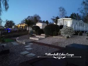 a backyard with a house and a fence and a yard at Meridian Tattershall Lakes Escape - Lakeside lodge caravan with a fishing peg LUXURY HOT TUB in Tattershall