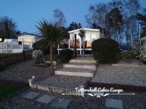 a house with a palm tree in the yard at Meridian Tattershall Lakes Escape - Lakeside lodge caravan with a fishing peg LUXURY HOT TUB in Tattershall