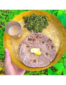 a person holding a plate with a plate of food at Hotel Mud House Auli, Joshimath, in Joshīmath