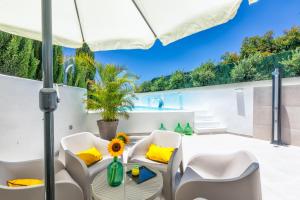 patio z białymi krzesłami i parasolem w obiekcie Bayton House w mieście Los Llanos de Aridane