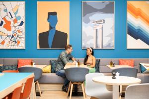 Ein Mann und eine Frau sitzen an Tischen in einem Restaurant in der Unterkunft Holiday Inn Express Antwerp - City Centre, an IHG Hotel in Antwerpen