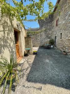 a courtyard of a building with a stone wall at Gîtes du Clos Cèze Art in Saint-André-de-Roquepertuis