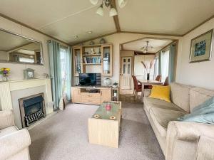 a living room with a couch and a fireplace at Lovely 6 Berth Caravan With Decking, Wifi And Onsite Beach Access Ref 68004cl in Lowestoft
