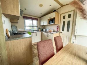 a small kitchen with a table and chairs in it at Lovely 6 Berth Caravan With Decking, Wifi And Onsite Beach Access Ref 68004cl in Lowestoft