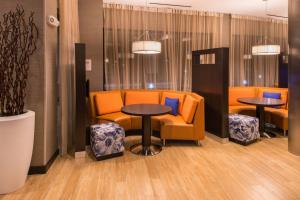 a waiting room with orange chairs and tables and chairs at Courtyard by Marriott Jacksonville in Jacksonville