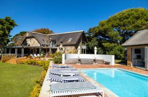 a house with a swimming pool and lounge chairs at Chapmans Peak Lodge Noordhoek Cape Town. in Cape Town