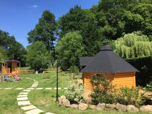 une petite maison en bois avec un toit noir dans un jardin dans l'établissement Les Roulottes De La Basse Maunerie, aux Herbiers